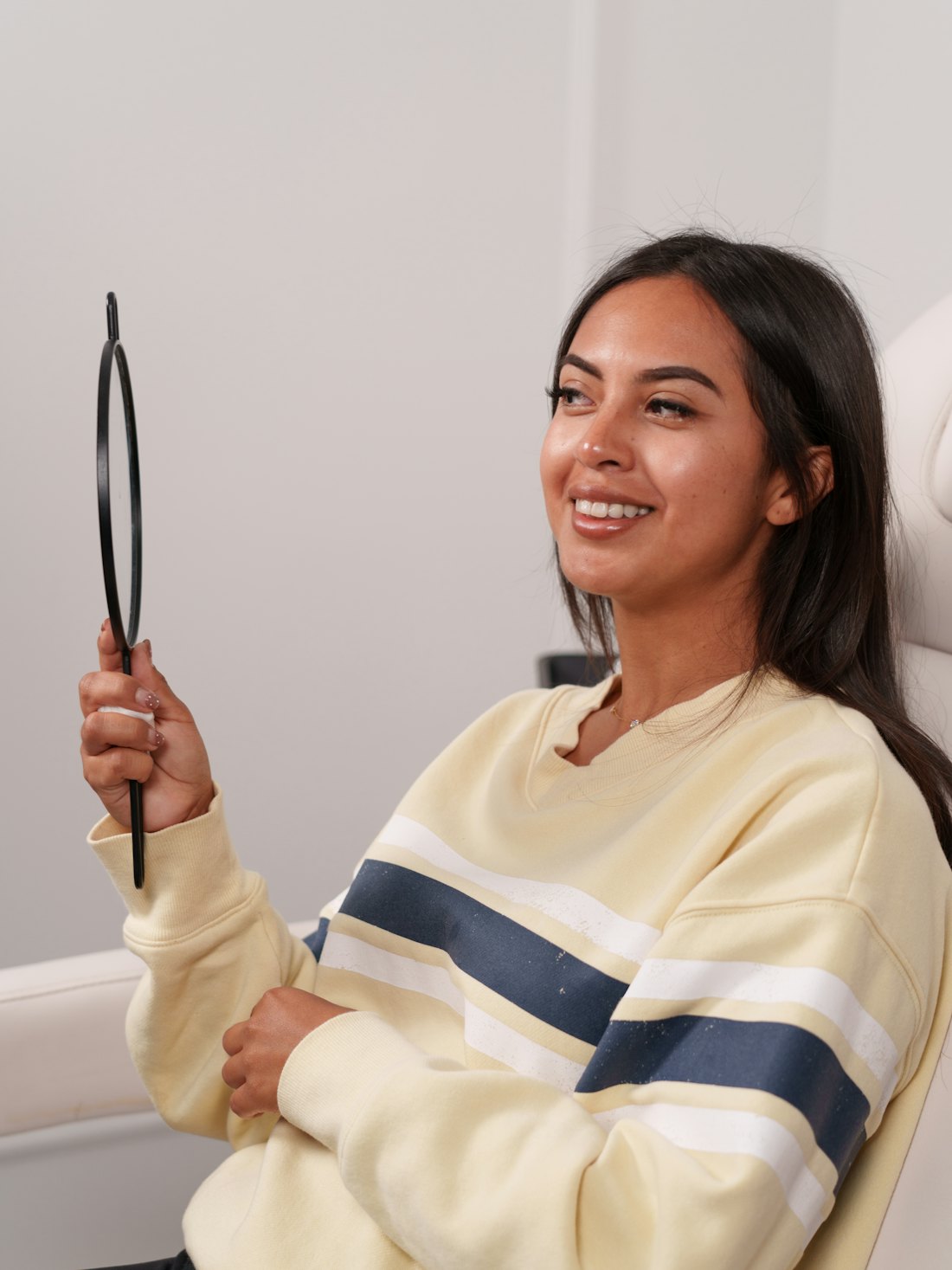 Patient smiling at her reflection after treatment